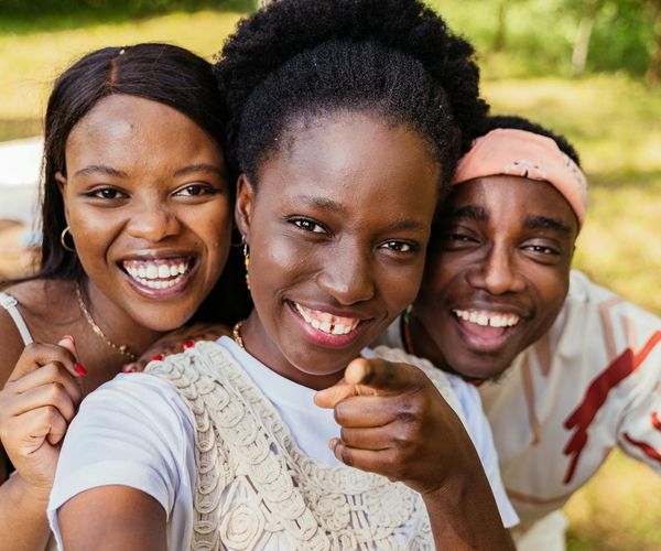 Diverse group of people smiling during a light yoga session outdoors.